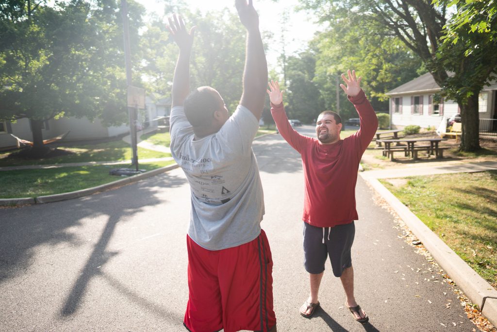 A Woods staff and resident reach up for a two-handed high five
